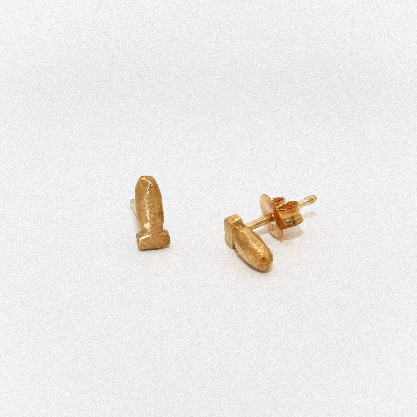 Gold bullet-shaped earrings on a white background