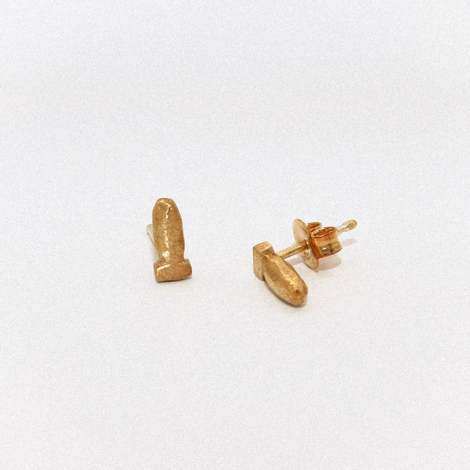 Gold bullet-shaped earrings on a white background