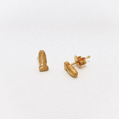 Gold bullet-shaped earrings on a white background