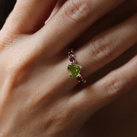 Close-up of a hand wearing a ring with a green gemstone.