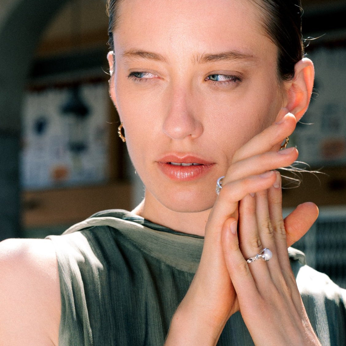 Woman with hands clasped, wearing a ring, in an indoor setting