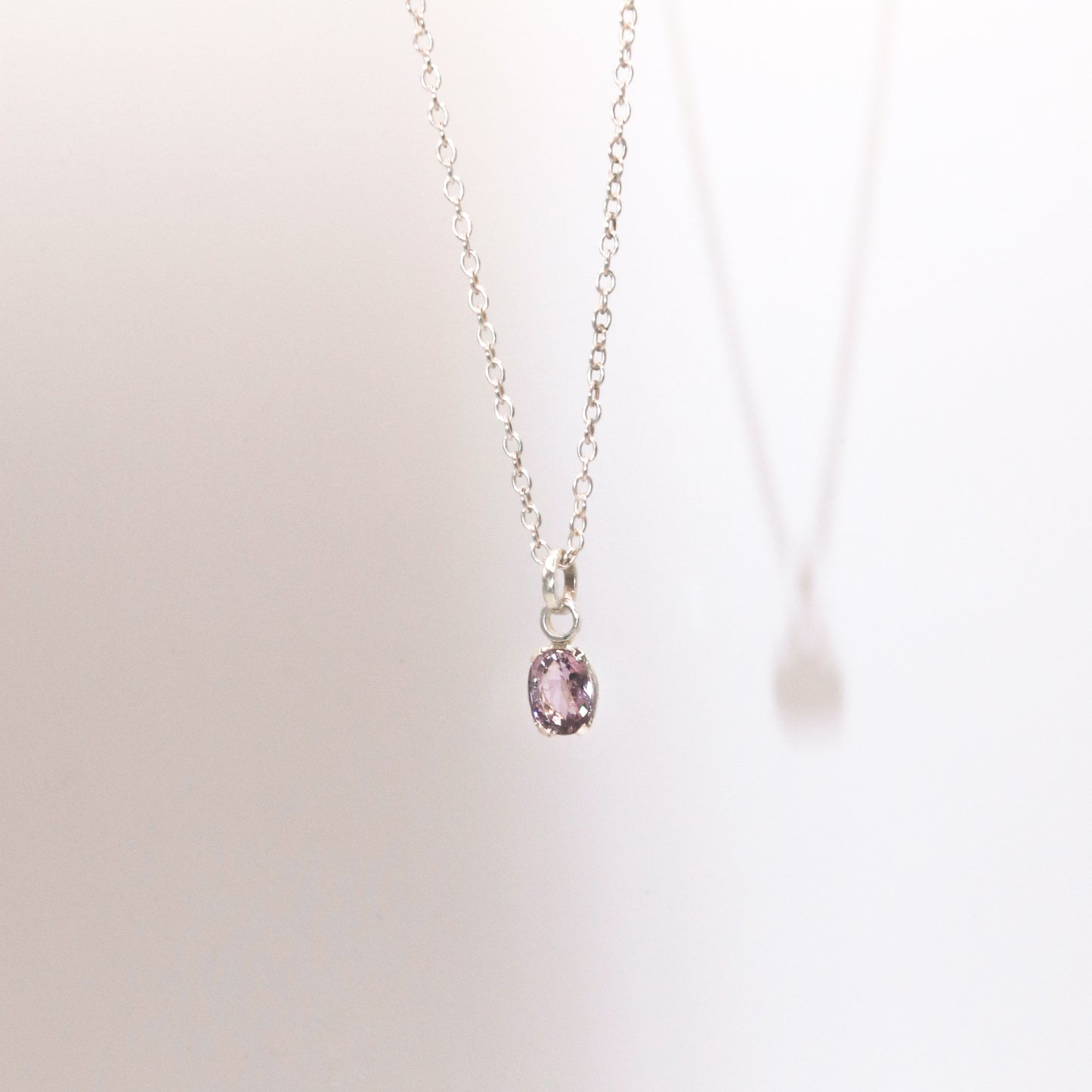 Necklace with a pink gemstone pendant on a light background