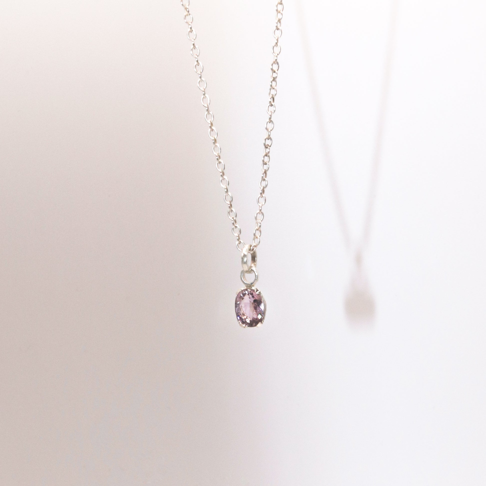 Necklace with a pink gemstone pendant on a light background