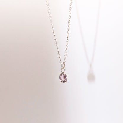 Necklace with a pink gemstone pendant on a light background