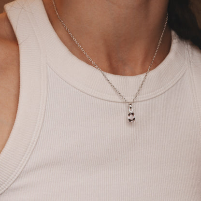 Silver necklace with a pendant worn by a person in a light-colored top
