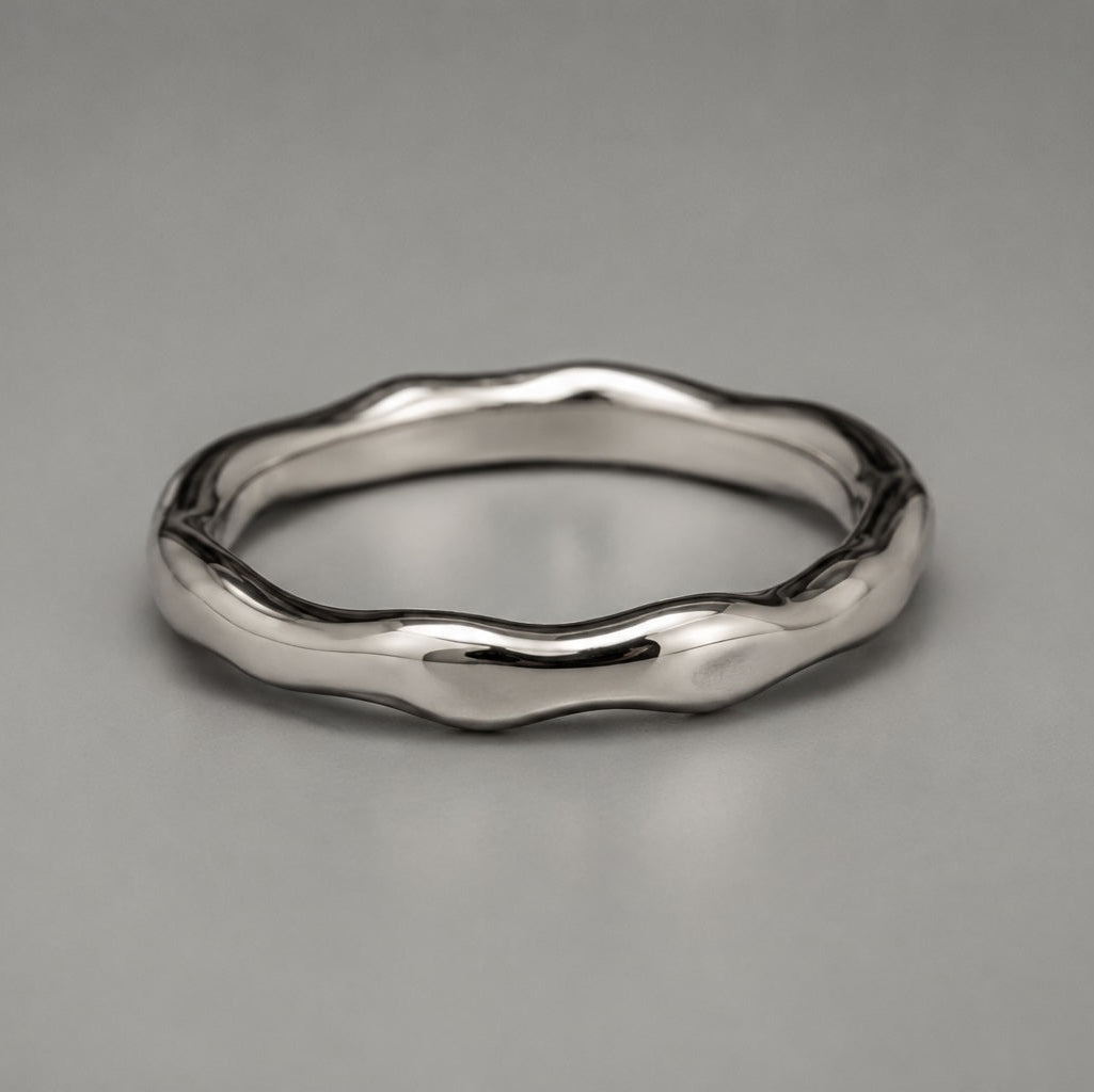 Silver ring with a wavy design on a gray background