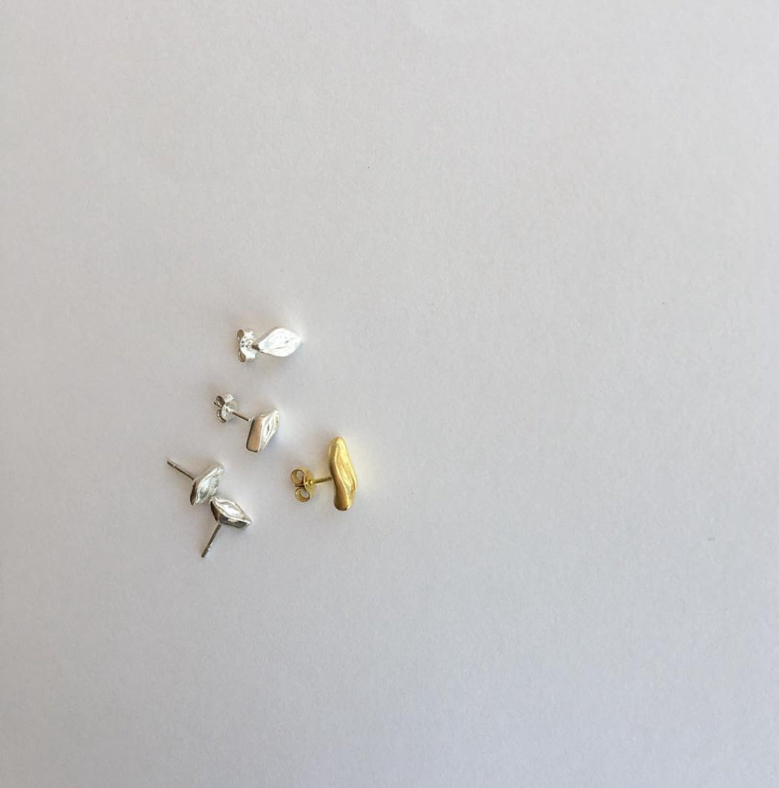 Three pairs of earrings in gold and silver on a light gray background