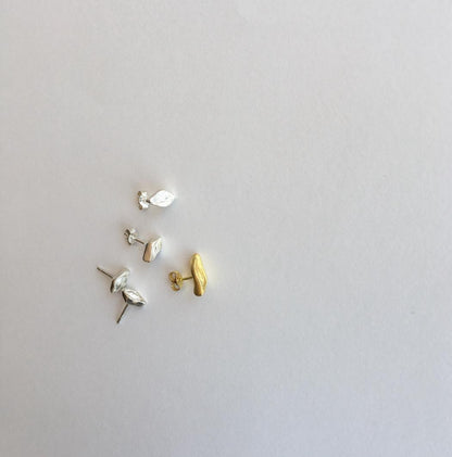 Three pairs of earrings in gold and silver on a light gray background