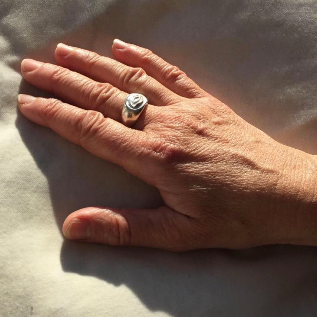 Hand wearing a ring on a light background