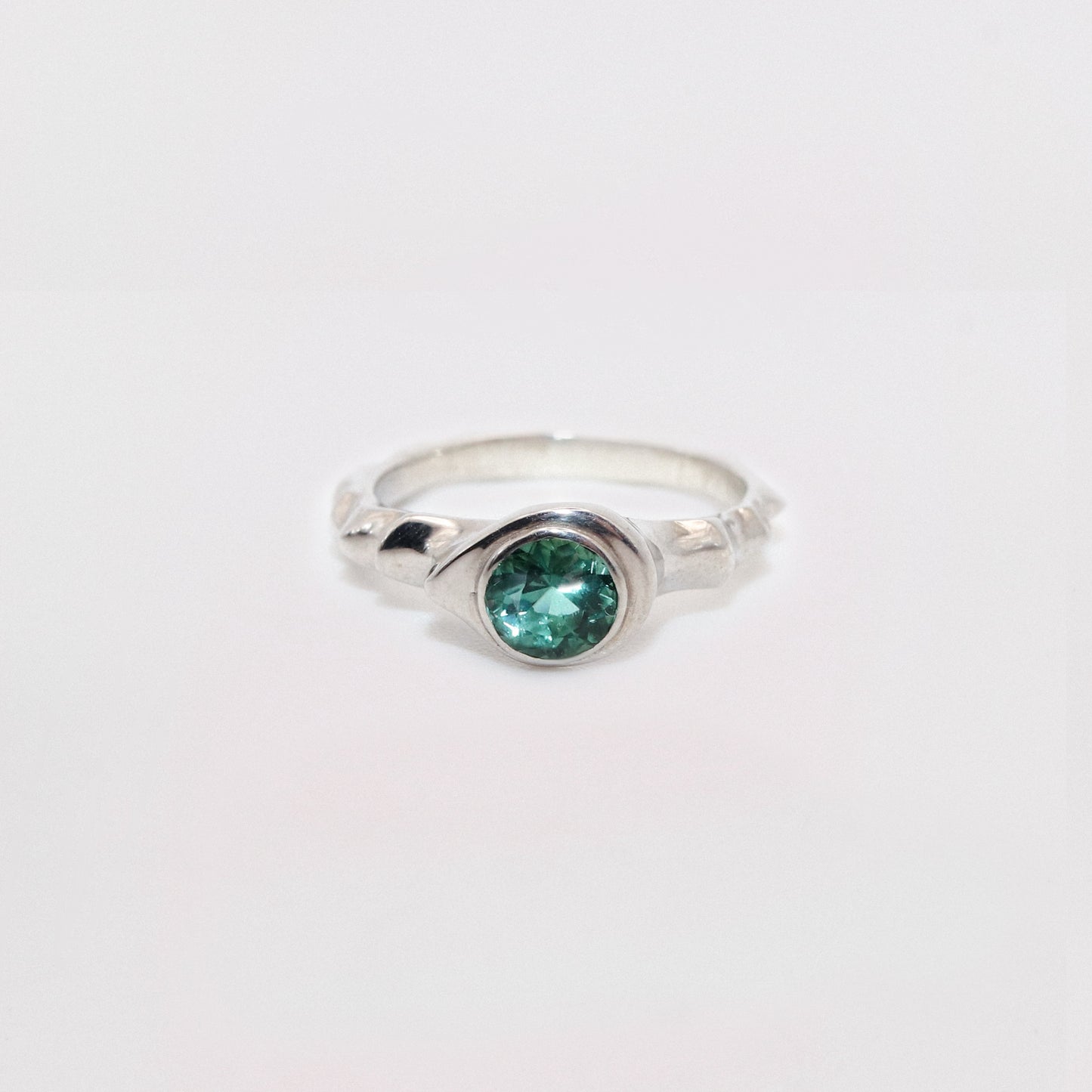 Silver ring with a green gemstone on a white background