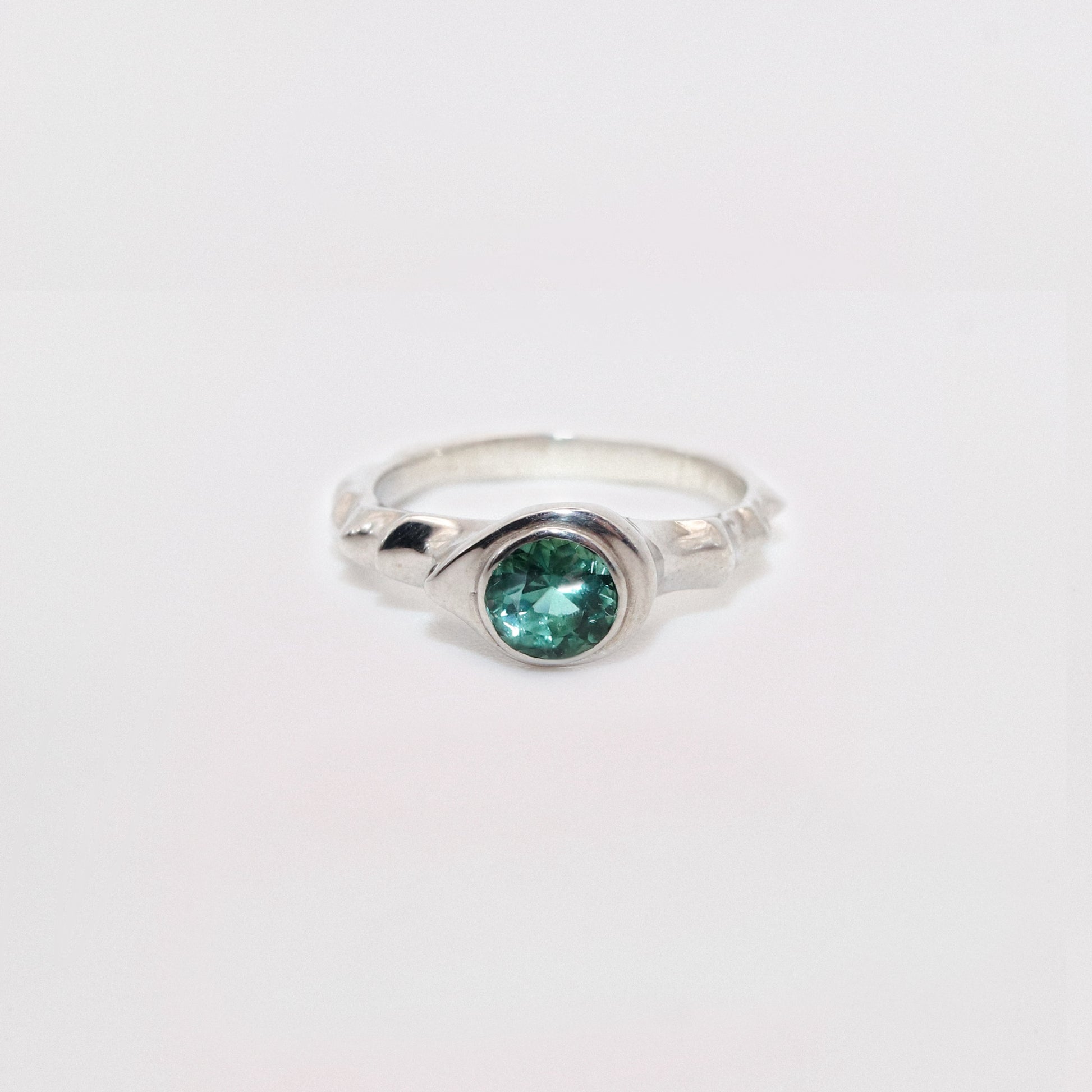 Silver ring with a green gemstone on a white background