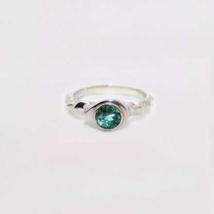 Silver ring with a green gemstone on a white background