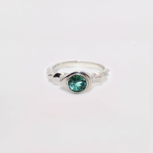 Silver ring with a green gemstone on a white background