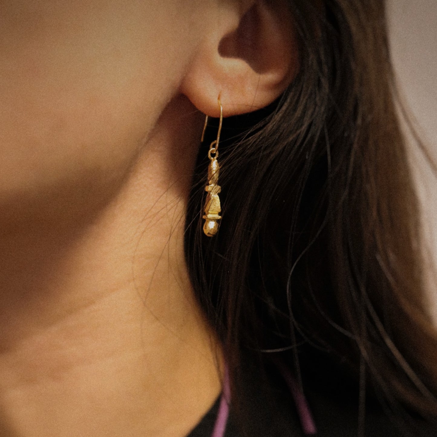 Close-up of a gold earring worn by a person with dark hair.