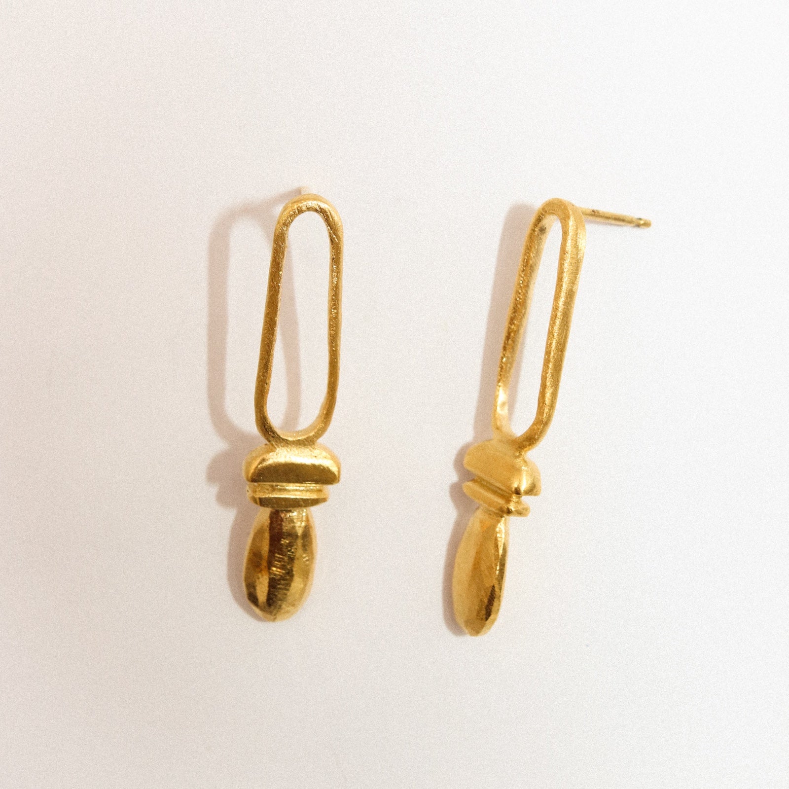 Pair of gold earrings on a light beige background