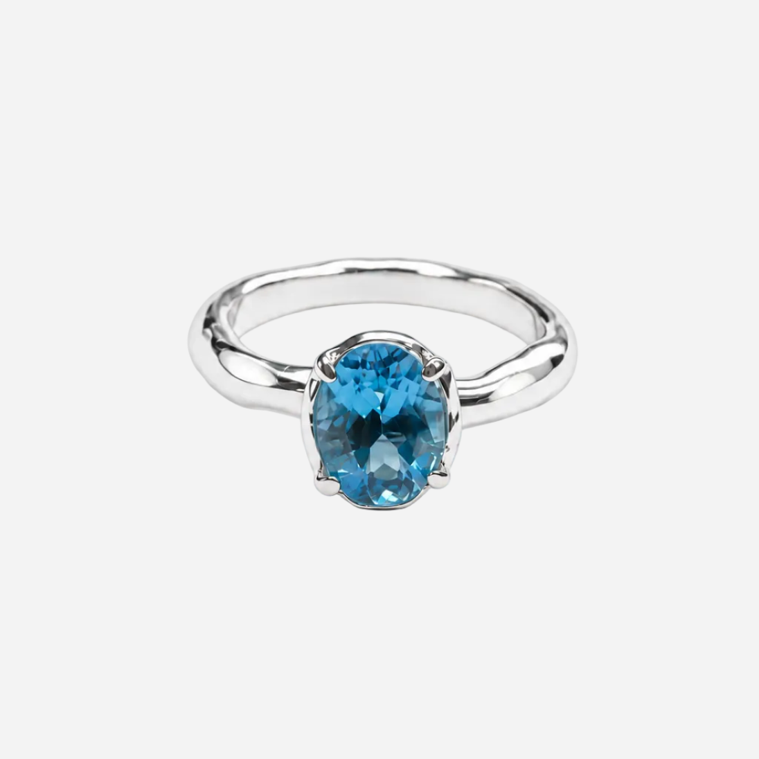 A silver ring featuring an oval-cut, vivid blue gemstone in a prong setting, shown on a clean white background.