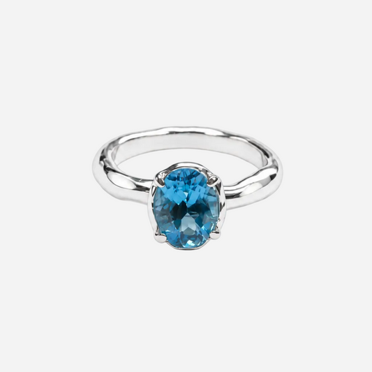 A silver ring featuring an oval-cut, vivid blue gemstone in a prong setting, shown on a clean white background.