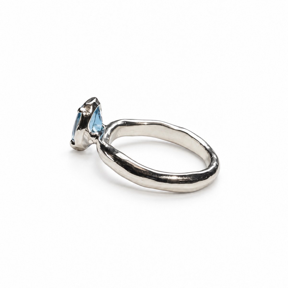 Silver ring with a blue topaz on a light gray background