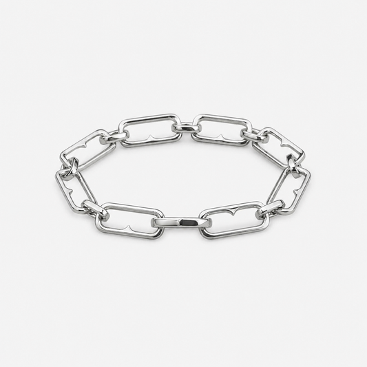 A polished silver-tone chain link bracelet with elongated, rounded rectangular links, displayed on a clean, light gray background.