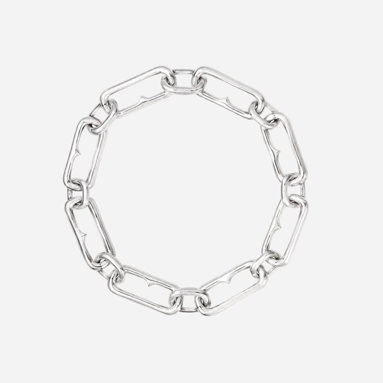 A silver paperclip chain bracelet arranged in a circle on a plain white background.
