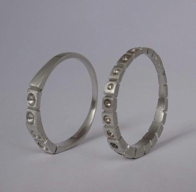 Two metallic rings with embedded stones on a gray background