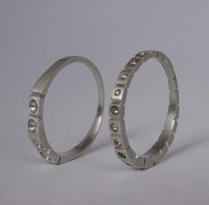 Two metallic rings with embedded stones on a gray background