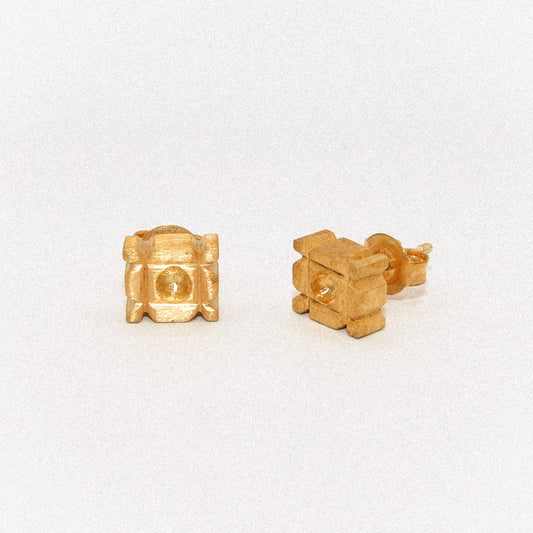 Gold stud earrings on a light gray background
