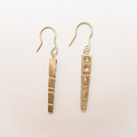 Pair of gold earrings on a light beige background