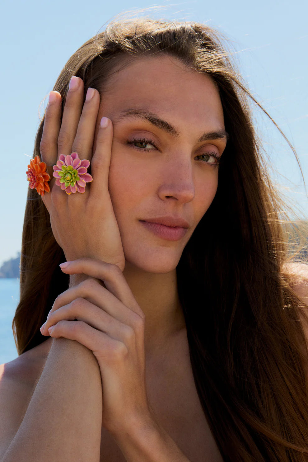 Woman with floral ring on hand against a clear blue sky