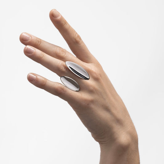 Hand wearing two silver rings on a light gray background
