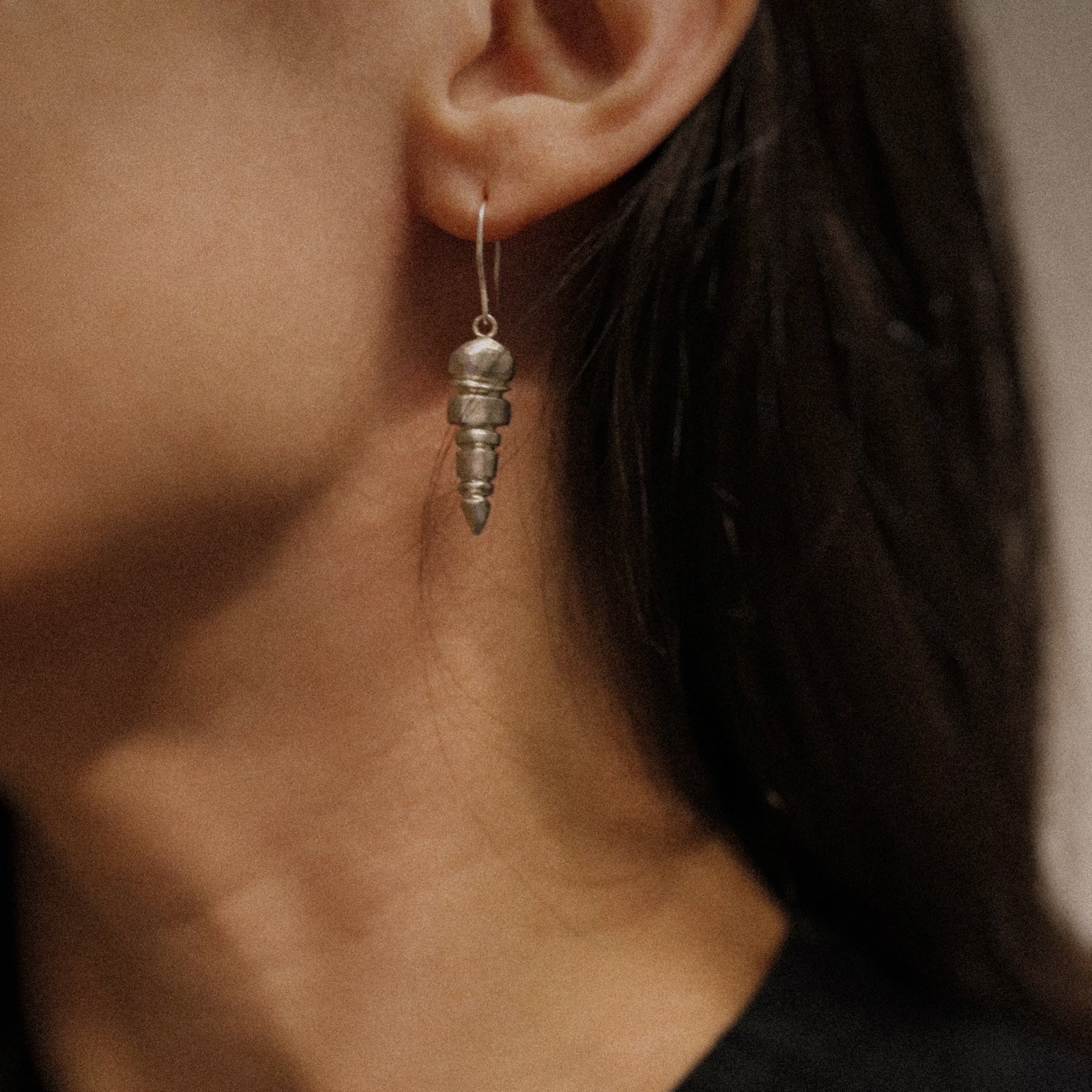 Close-up of a person wearing a silver spiral earring with a blurred background