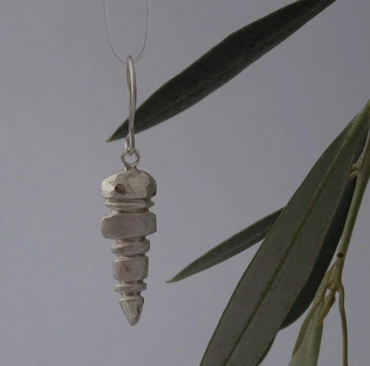 Silver pendant on a chain with a leafy background