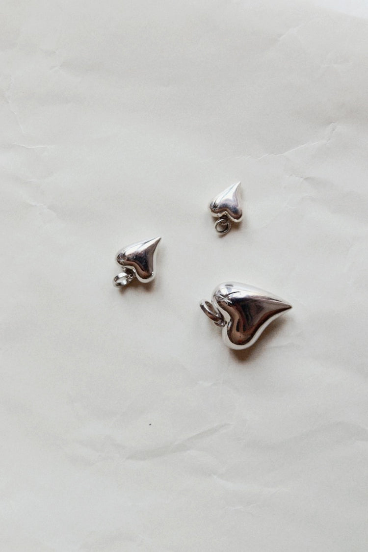 Silver heart pendants on pale paper at Dune Workshop