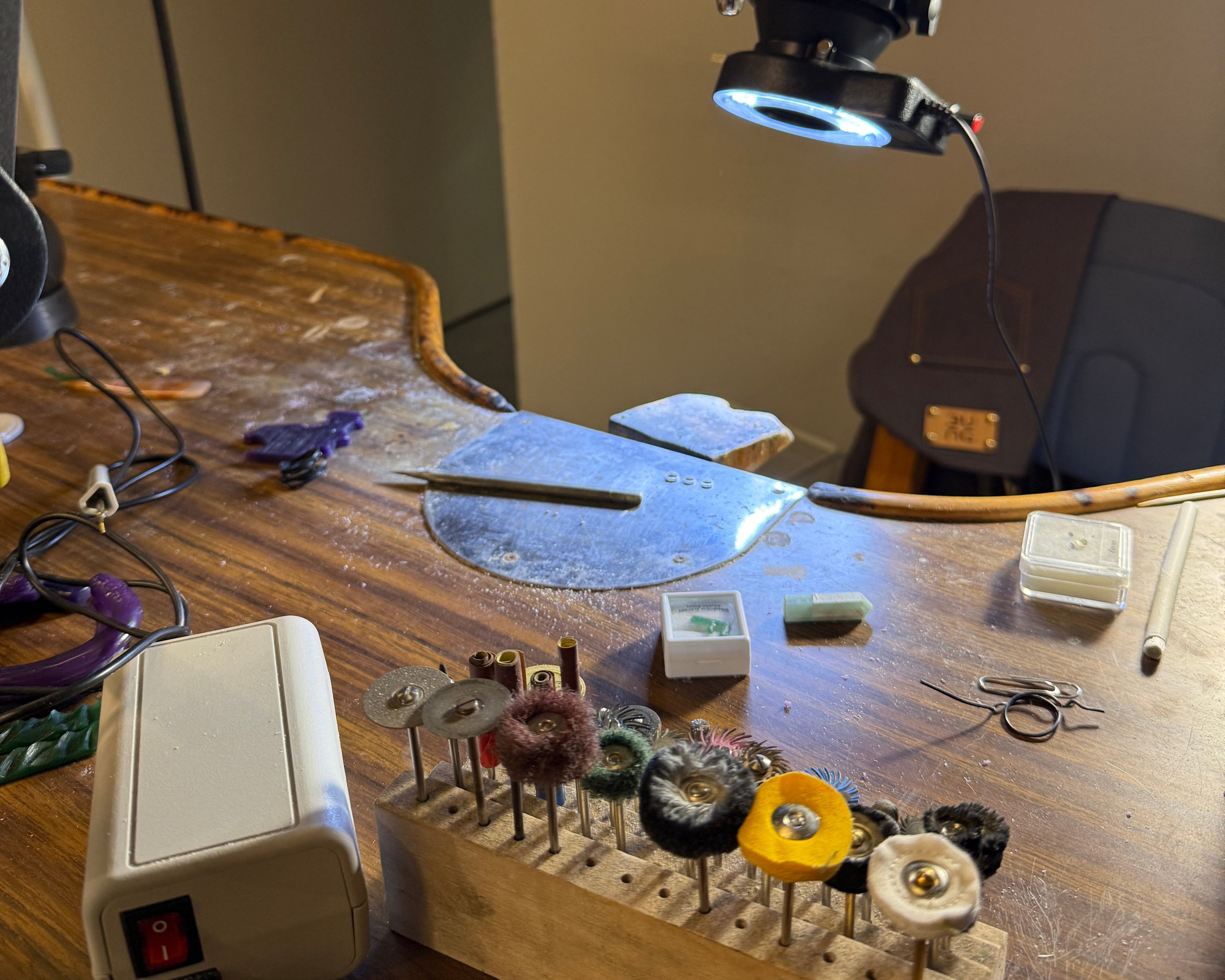 Close-up of a mechanical device on a wooden workbench with tools and equipment.