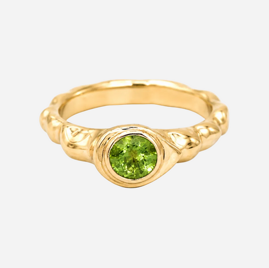 Gold ring with a green gemstone on a white background