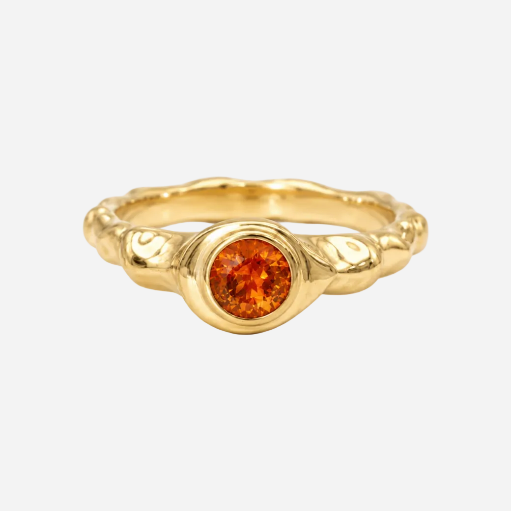 Gold ring with a red gemstone on a white background