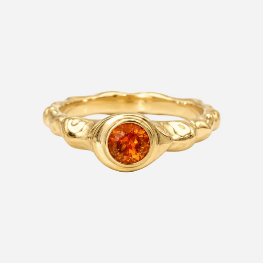 Gold ring with a red gemstone on a white background