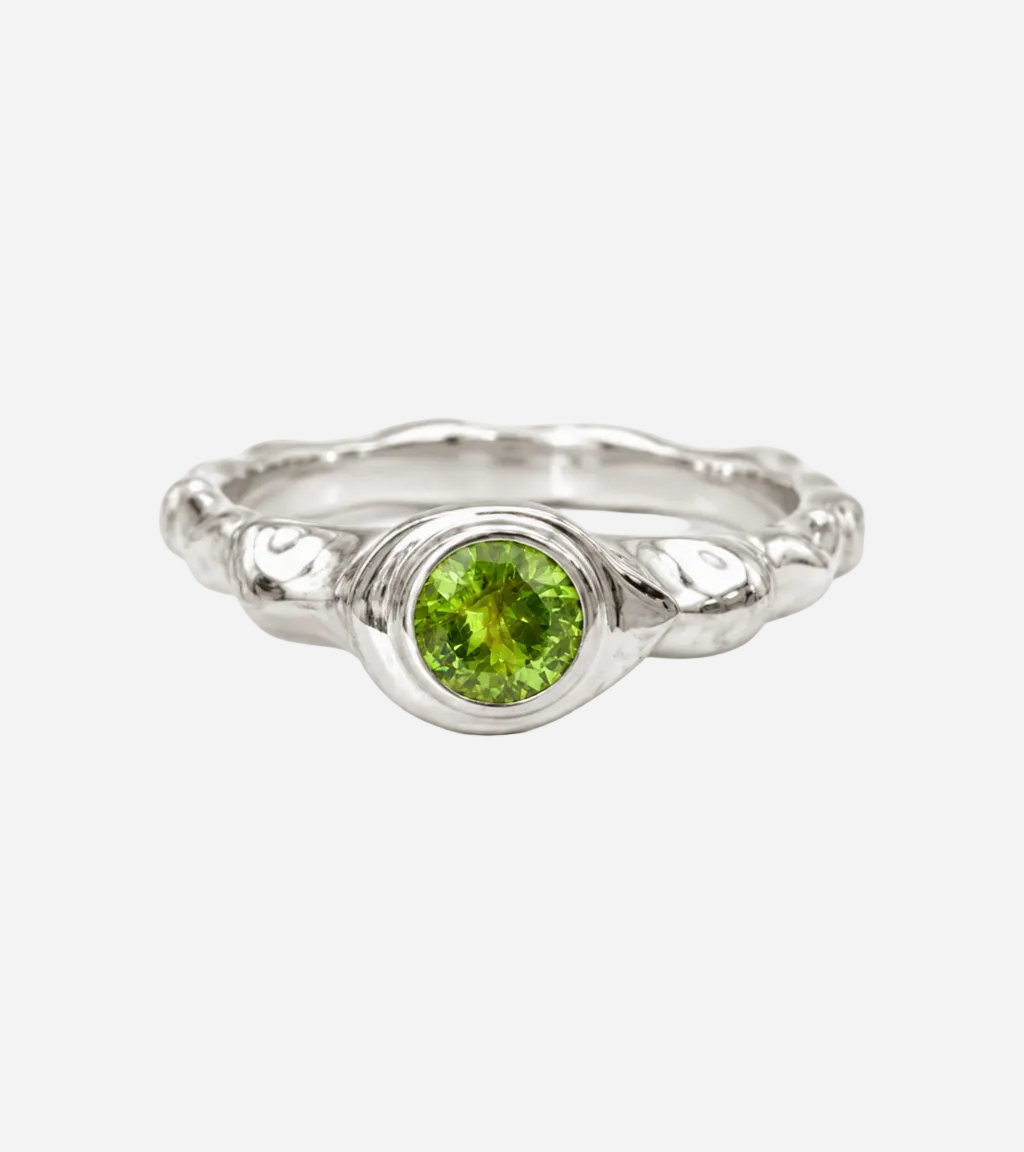 Silver ring with a green gemstone on a white background