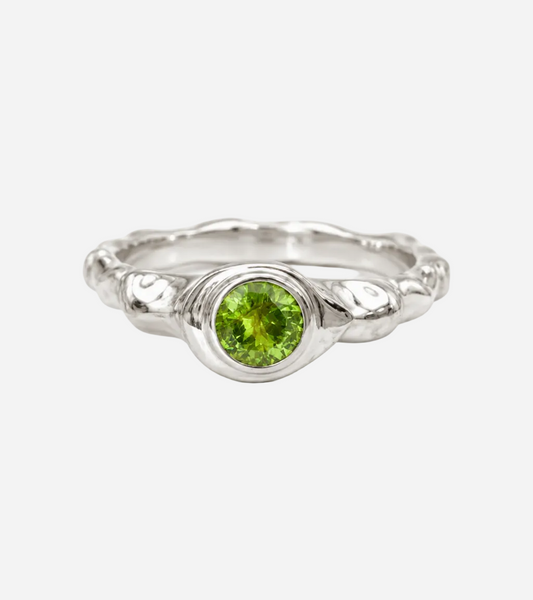 Silver ring with a green gemstone on a white background