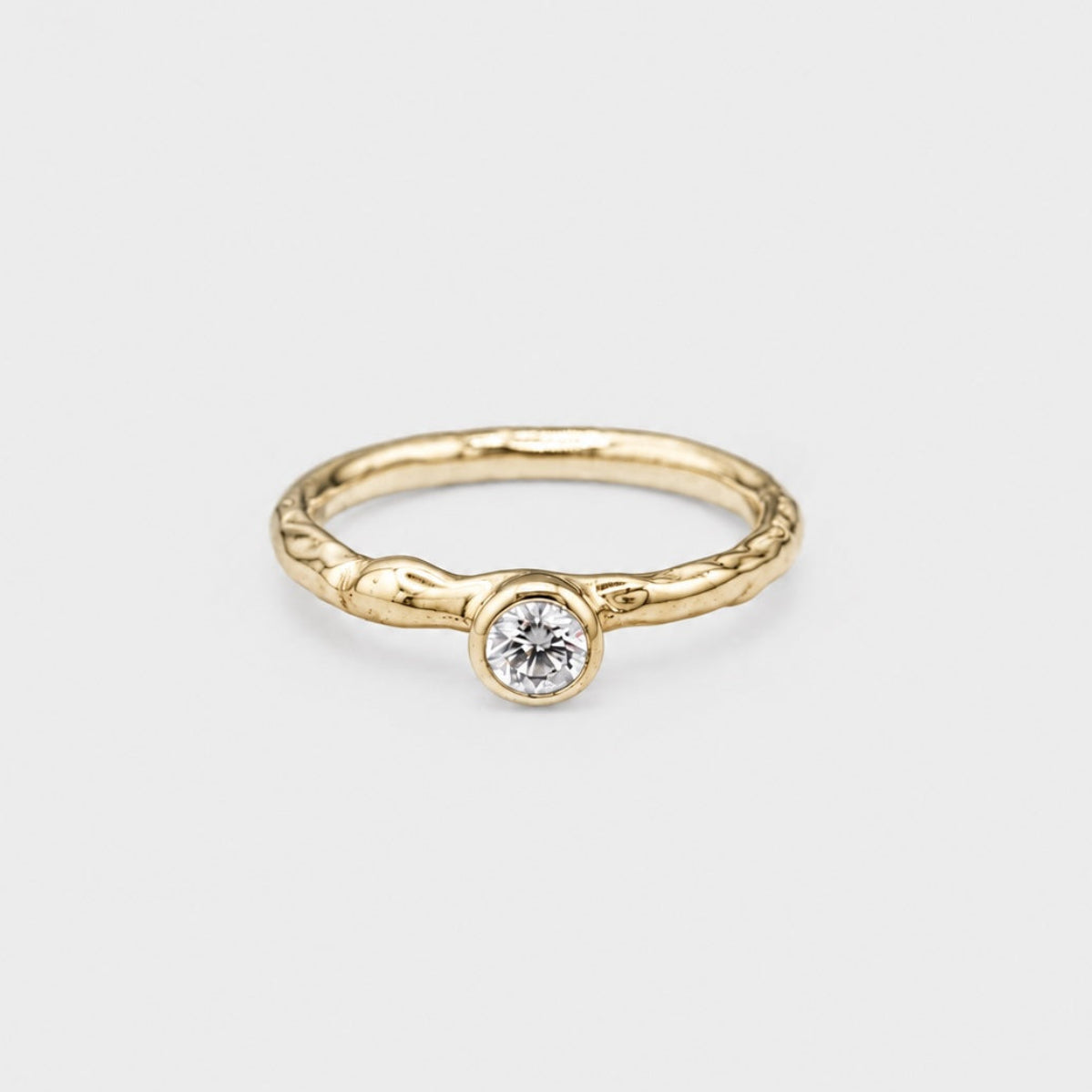 Gold ring with a diamond on a light gray background