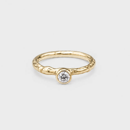 Gold ring with a diamond on a light gray background