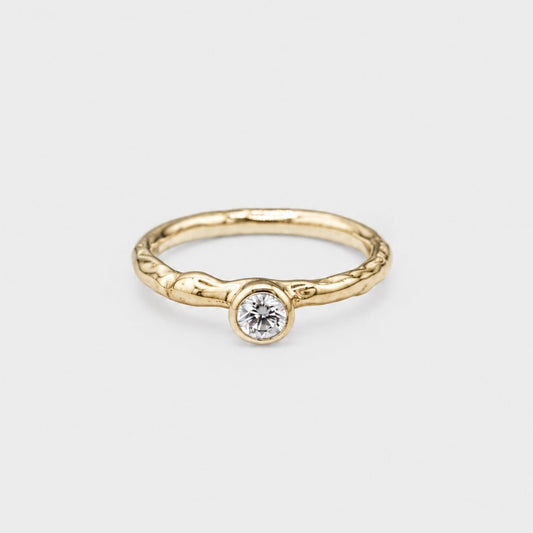 Gold ring with a diamond on a light gray background