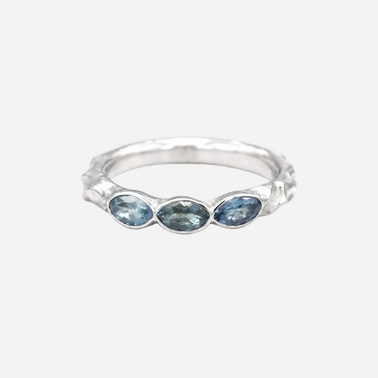 Silver ring with three blue gemstones on a white background