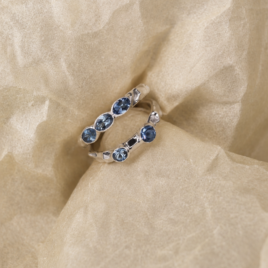 Silver ring with blue gemstones on beige fabric