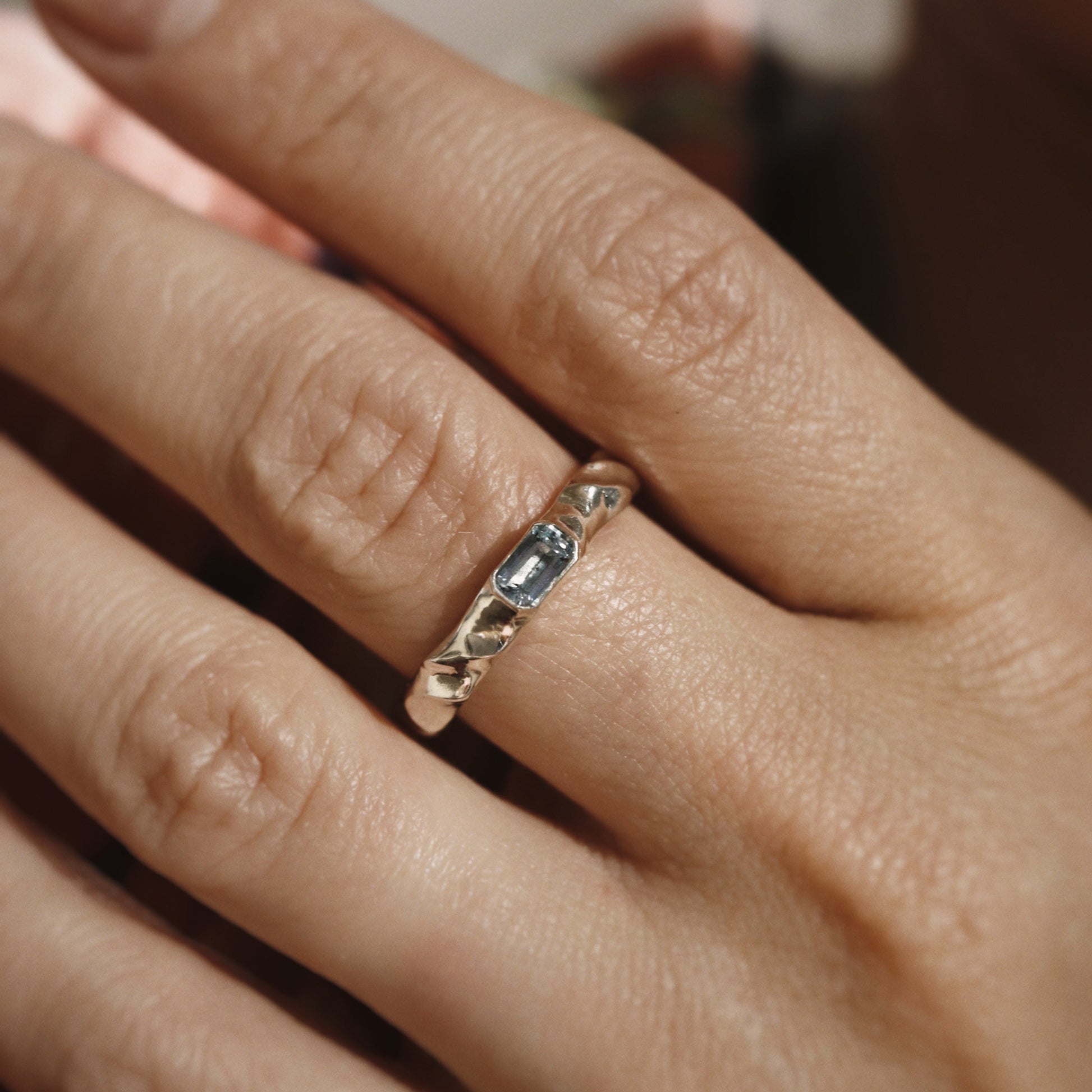 Close-up of a hand wearing a gold ring with a gemstone.