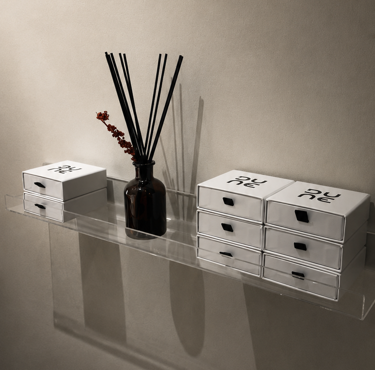 Set of white drawers with black handles on a reflective surface against a beige wall.
