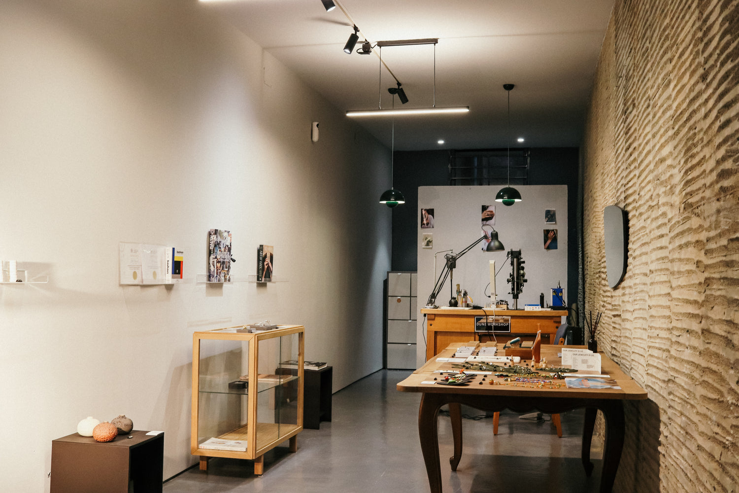 Modern office or studio with wooden furniture, shelves, and a textured wall.