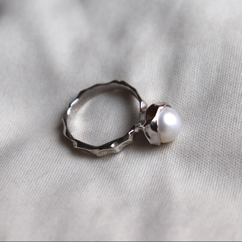 Silver ring with a pearl on a light gray fabric background