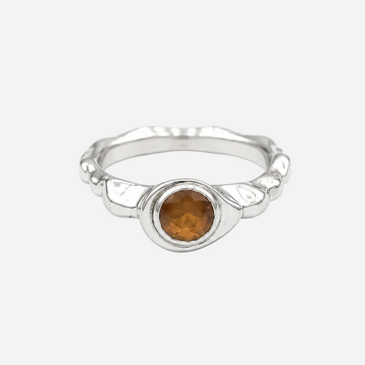 Silver ring with a round amber stone on a white background