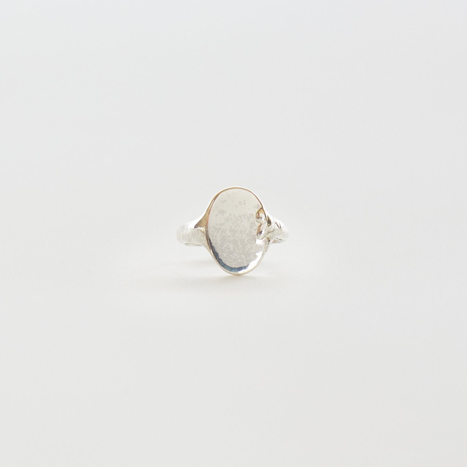 Silver ring with a textured band on a light gray background